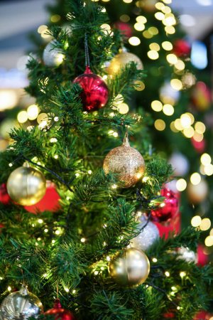 Photo for Selective focus on the golden ball decorated on the Christmas tree with the bokeh lights in background. Party and celebration in Christmas festival - Royalty Free Image