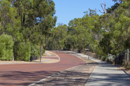 Street View der hügeligen Maidment Parade, Dalyellup, Westaustralien mit dem Radweg, der an die Kalgulup Regional Parklands angrenzt und die großzügigen Ranch-großen Grundstücksblöcke mit großen Häusern und Bäumen enthält.