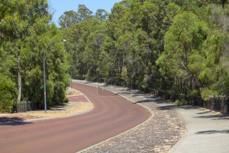 Street View der hügeligen Maidment Parade, Dalyellup, Westaustralien mit dem Radweg, der an die Kalgulup Regional Parklands angrenzt und die großzügigen Ranch-großen Grundstücksblöcke mit großen Häusern und Bäumen enthält.