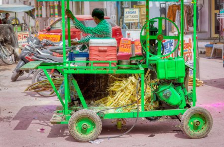 Foto de PUSHKAR, INDIA - 3 DE MARZO DE 2018: Colorida escena del vendedor de jugo de caña de azúcar seling en la calle de la Ciudad Santa. - Imagen libre de derechos