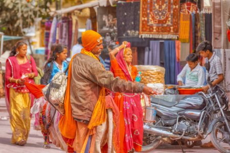 Foto de PUSHKAR, INDIA - MARCH 3 2018: Colorful scene of sadhu asking for charity on the street of the Holy City. - Imagen libre de derechos