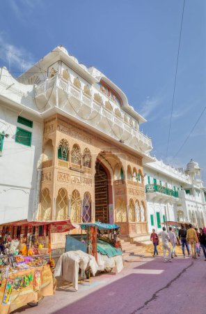 Foto de PUSHKAR, INDIA - MARCH 3 2018: Street view of the Shree Rma Vaikunth Mandir temple entrance at afternoon siesta time with visitors and passers by. - Imagen libre de derechos