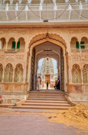 Foto de PUSHKAR, INDIA - MARCH 3 2018: Street view of the Shree Rma Vaikunth Mandir temple entrance at afternoon siesta time with visitors and passers by. - Imagen libre de derechos