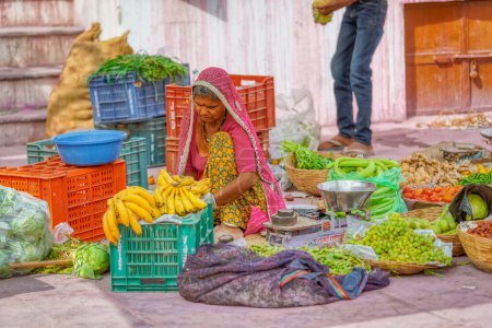 Photo for PUSHKAR, INDIA - MARCH 3 2018: Colorful scene of woman selling fruits and vegetables on the street market. - Royalty Free Image