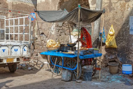 Foto de AJMER, INDIA - MARCH 3 2018: Colorful scene of street food seller and people on the Dargah Bazar road of the old city center. - Imagen libre de derechos