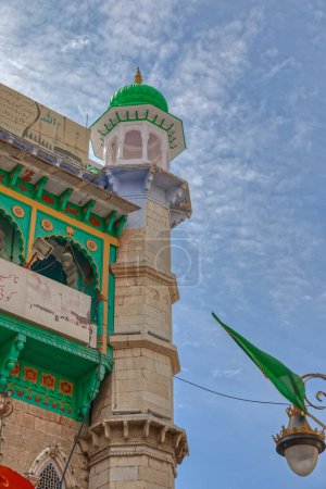 Foto de AJMER, INDIA - 3 DE MARZO DE 2018: Colorido minarete en la puerta de entrada del templo Dargah Shariff en el centro de la ciudad vieja. - Imagen libre de derechos