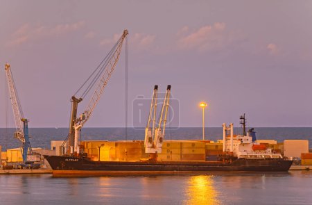 Foto de BARI, ITALIA - 26 de septiembre de 2019 Reconstrucción del rompeolas en el puerto de contenedores al atardecer. - Imagen libre de derechos