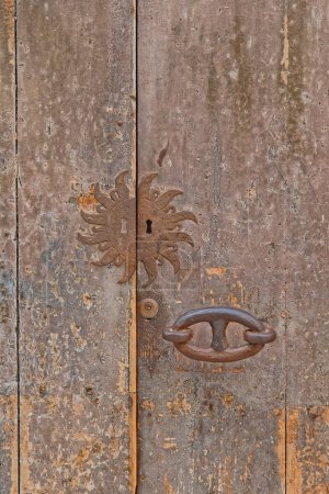 Foto de Puerta de madera vieja con diseño de sol de metal en Bari Italia. - Imagen libre de derechos