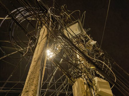 Foto de Un poste eléctrico con un enredo de cables en la calle oscura del casco antiguo por la noche. larga exposición - Imagen libre de derechos