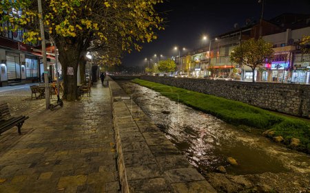 Photo for PRIZREN, KOSOVO - NOVEMBER 12, 2022: People walking by pedestrian bridge with blue fence and river Bistrica in city center on cold november night. long exposure - Royalty Free Image