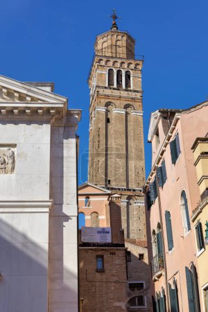 Téléchargez les photos : Ancien clocher Saint Stephen jette un coup d'oeil élégant à travers le labyrinthe des maisons vénitiennes. - en image libre de droit