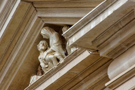 Téléchargez les photos : Sculpture piéta complexe au sommet d'une église vénitienne sous les poutres du toit, symbole de dévotion religieuse et d'art. - en image libre de droit