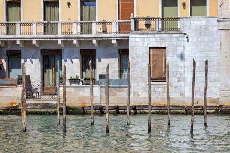 Téléchargez les photos : Poteaux d'amarrage en bois dans le Grand Canal de Venise sans gondoles attachées, façade de la vieille maison en arrière-plan. - en image libre de droit