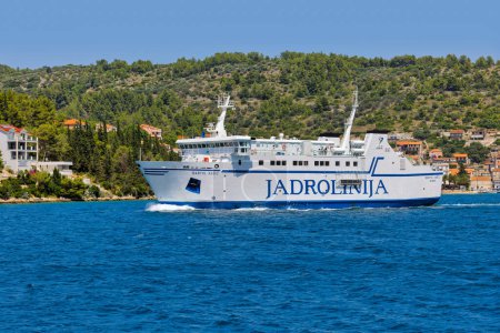 Téléchargez les photos : Le ferry Bartol Kasic part du port pittoresque de Vela Luka, marquant une autre journée ensoleillée en Croatie. - en image libre de droit