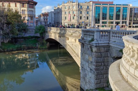 Foto de PADUA, ITALIA - 01 ABRIL 2023: Gente paseando por la calle Giuseppe Garibaldi con la vista del Ponte del Popolo y su sereno reflejo del río. - Imagen libre de derechos