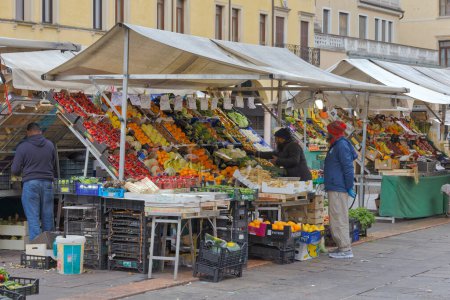 Foto de PADUA, ITALIA - 02 ABRIL 2023: El bullicio de la mañana en Piazza delle Erbe, con vendedores de verduras y frutas puestos en exhibición. - Imagen libre de derechos