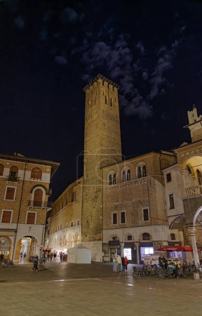 Téléchargez les photos : PADUA, ITALIE - 03 AVRIL 2023 : Scène de vie nocturne avec des personnes se promenant au clair de lune sur la Piazza della Frutta dominée par le Palazzo della Ragione. - en image libre de droit