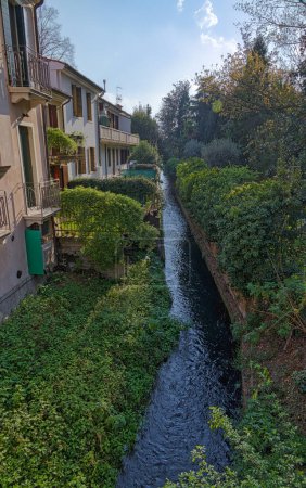Photo for A view of an aged building facade and an green nature of the medieval channel in Padua Italy. - Royalty Free Image