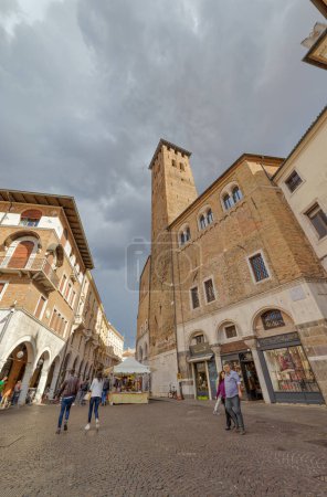 Foto de PADUA, ITALIA - 03 DE ABRIL DE 2023: La animada vida en Piazza della Frutta bajo los cielos nublados, con el Palazzo della Ragione y la antigua torre - Imagen libre de derechos