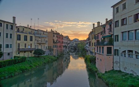 Photo for Sunset illuminating the vintage facades and arch bridge over a medieval canal in Padua Italy. - Royalty Free Image