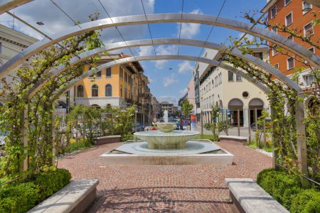 Foto de SAN DONA DI PIAVE, ITALIA - 28 de julio de 2023: Una vibrante vista de Piazza Angelo Trevisan con una floreciente fuente rodeada de flores. - Imagen libre de derechos
