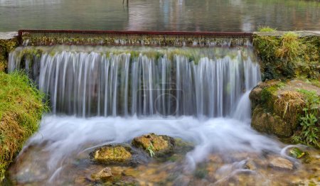 Foto de Pequeña cascada de rejilla metálica que controla expertamente el flujo de agua en un pintoresco arroyo en Travnik, Bosnia y Herzegovina. - Imagen libre de derechos