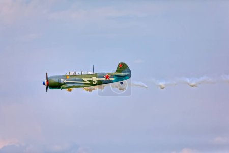 Téléchargez les photos : VARAZDIN, CROATIE - 21 juillet 2018 : Un avion préservé de la Seconde Guerre mondiale laisse une trace de fumée pendant son vol lors d'un spectacle aérien. - en image libre de droit