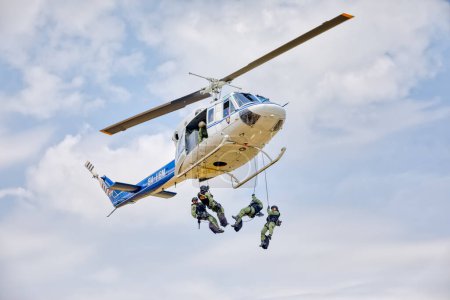 Foto de VARAZDIN, CROACIA - 21 de julio de 2018: Oficiales de unidades especiales de policía que descienden de un helicóptero Agusta Bell AB 212ASW con cuerdas durante un ejercicio de demostración. - Imagen libre de derechos