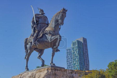 Foto de TIRANA, ALBANIA - 20 de octubre de 2019: Estatua de bronce de Skenderbeg a caballo con la moderna Forever Green Tower al fondo. - Imagen libre de derechos