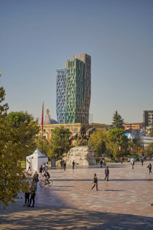 Photo for TIRANA, ALBANIA - October 20, 2019: Skenderbeg Square with pedestrians and the modern Forever Green Tower in the background. - Royalty Free Image
