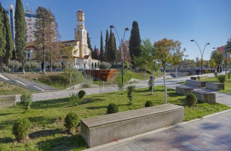 Téléchargez les photos : FIER, ALBANIE - 20 octobre 2022 : Vue panoramique du parc de la ville et du canal orné de la rivière Gjanica qui coule devant la cathédrale orthodoxe Saint-Georges. - en image libre de droit