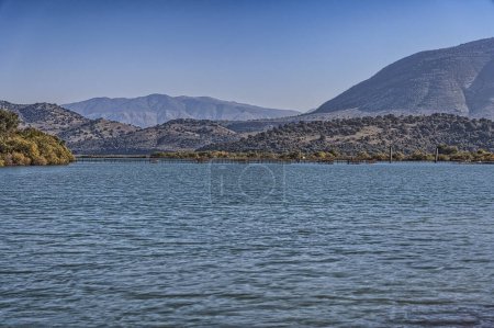 Téléchargez les photos : Vue sereine de la Manche de Vivari à Butrint, Albanie avec une mytiliculture lointaine. - en image libre de droit