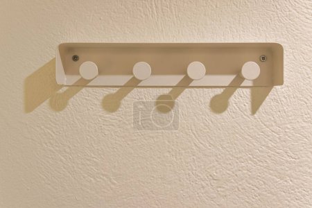 Photo for A monochrome portrayal of a metal clothes hanger with four holders affixed to a wall - Royalty Free Image