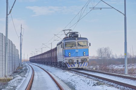 Téléchargez les photos : KRIZEVCI, CROATIE - 25 janvier 2023 : Une locomotive électrique bleue entraîne un long train de marchandises le long des voies enneigées du chemin de fer. - en image libre de droit