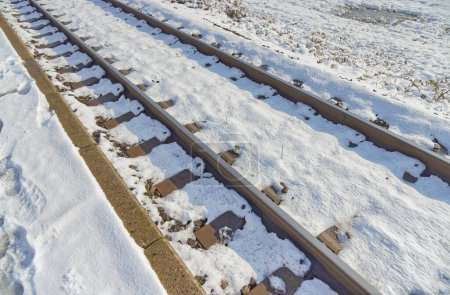 Téléchargez les photos : Gros plan détaillé des voies ferrées enneigées mettant en évidence le contraste entre les rails en acier et la neige blanche à Dugo Selo. - en image libre de droit