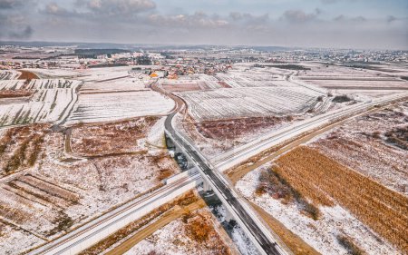Téléchargez les photos : Des routes se croisent dans un champ neigeux près de Krizevci, en Croatie, vues d'en haut, mettant en évidence le contraste entre la nature et les infrastructures. - en image libre de droit