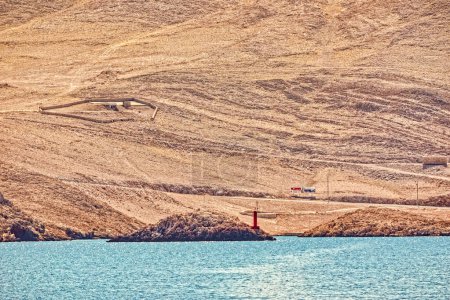 Téléchargez les photos : ZIGLJEN, CROATIE - 2 septembre 2020 : Paysage aride et phare rouge marquant l'entrée du port de Zigljen sur l "île de Pag - en image libre de droit