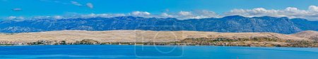Photo for Breathtaking panorama of the arid Pag Island landscape with Velebit Mountain rising in the distance under the blue sky. - Royalty Free Image