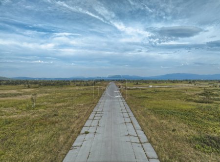 Téléchargez les photos : Perspective aérienne d'une piste d'atterrissage abandonnée depuis longtemps avec usure évidente, nichée dans un terrain montagneux à Zeljava. - en image libre de droit