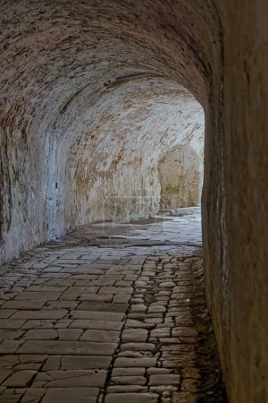 Foto de Arco de piedra dentro de la histórica Fortaleza Vieja de Corfú, mostrando el camino de mampostería envejecida y adoquinado. - Imagen libre de derechos