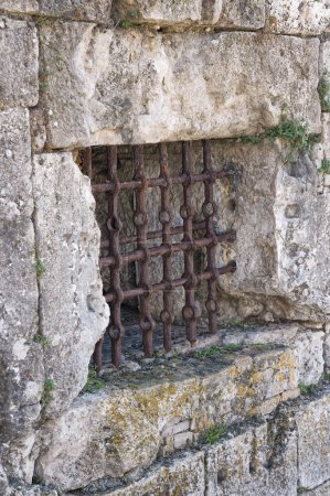 Foto de Barras de hierro oxidado en una ventana de pared de piedra en la antigua fortaleza de Corfú, mostrando la antigua defensa arquitectónica griega. - Imagen libre de derechos