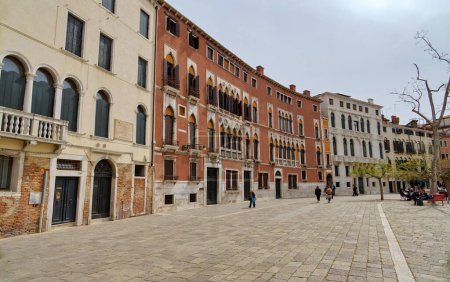 Téléchargez les photos : VENISE, ITALIE - 11 AVRIL 2023 : : Les gens marchent à travers une place pittoresque près de la vieille église dans le quartier de Cannaregio, encadrée par des façades historiques et l'atmosphère sereine. - en image libre de droit