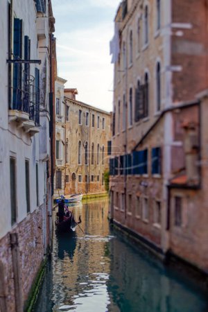 Photo for VENICE, ITALY - APRIL 11 2023: A gondolier skillfully navigates a winding canal in Venices historic center, offering a glimpse into the timeless charm of this iconic city. tilt shift lens - Royalty Free Image