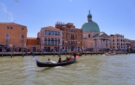 Photo for VENICE, ITALY - APRIL 10 2023: Gondola passing by the capturing old buildings and the green domed Banca Monte dei Paschi di Siena in Grand canal. - Royalty Free Image
