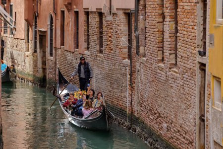 Téléchargez les photos : VENISE, ITALIE - 11 AVRIL 2023 : Un gondolier parcourt habilement un canal sinueux du centre historique de Venices, offrant un aperçu du charme intemporel de cette ville emblématique. - en image libre de droit