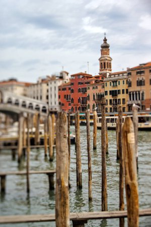 Foto de VENECIA, ITALIA - 11 DE ABRIL DE 2023: Un pintoresco puerto deportivo se detiene con el paso del barco y el puente de Rialto en el Gran Canal. lentes de desplazamiento basculante - Imagen libre de derechos