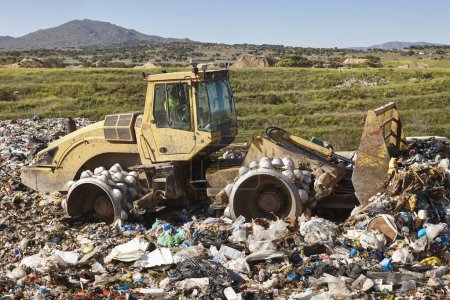 Photo for Heavy machinery shredding garbage in an open air landfill. Waste - Royalty Free Image