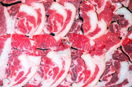 Foto de Slide raw beef for Yakiniku. Thin piece beef for Shabu hotpot japanese food style. Close up fresh meat chuck eye for Sukiyaki. top view. - Imagen libre de derechos