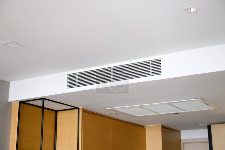 Acondicionador de aire por conducto para casa u oficina. Acondicionador de aire tipo casete montado en el techo y luz moderna de la lámpara en el techo blanco.