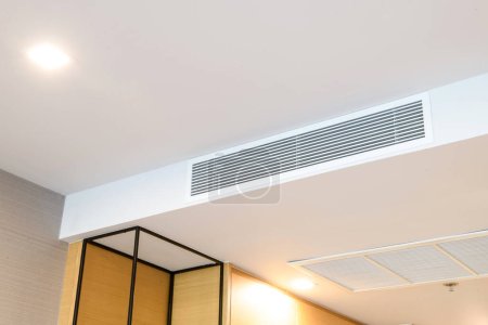 Acondicionador de aire por conducto para casa u oficina. Acondicionador de aire tipo casete montado en el techo y luz moderna de la lámpara en el techo blanco.